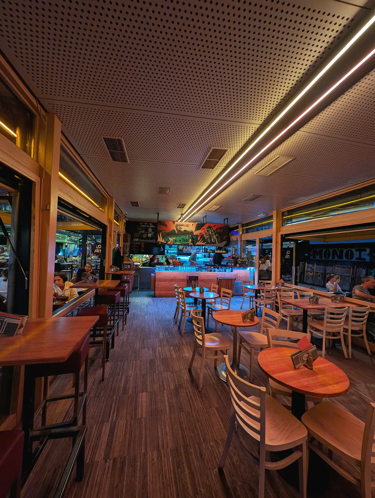 Innenraum des Cafe Do-An mit Holztischen, Sesseln und Lichtleisten an der Decke