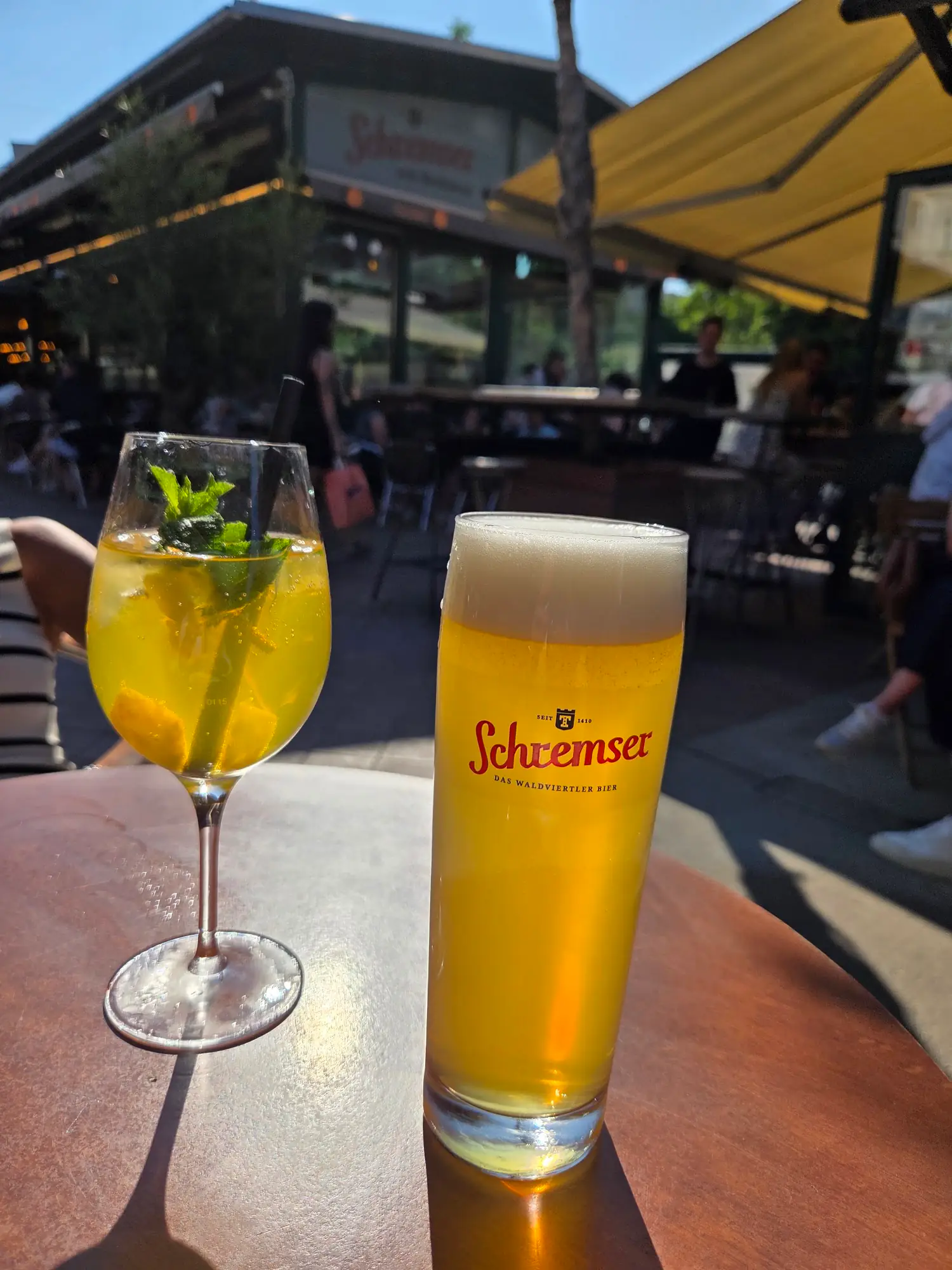 Frisch gezapftes Bier und Cocktail mit Minze auf einem Terrassentisch